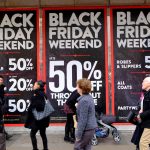 Shoppers walk past a department store with signs reading “Black Friday weekend, 50% off”. Oxford Street, London